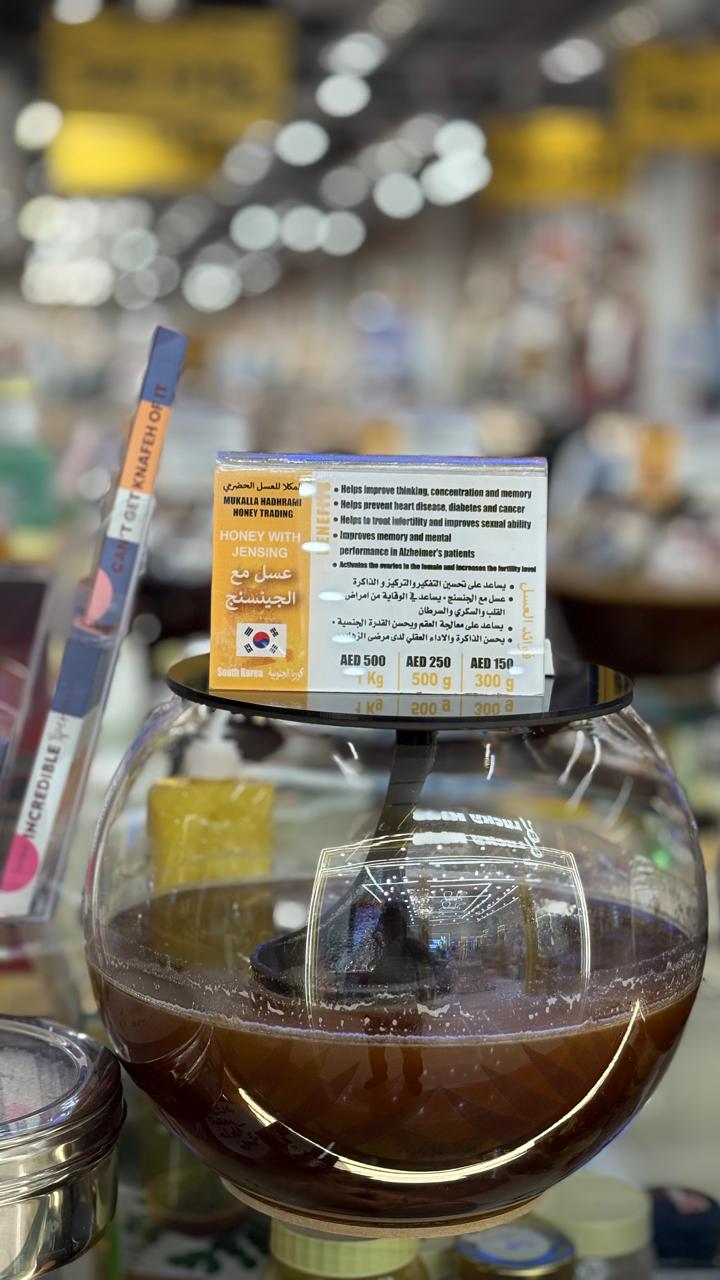 Honey with ginseng in a spherical glass jar with branded label.