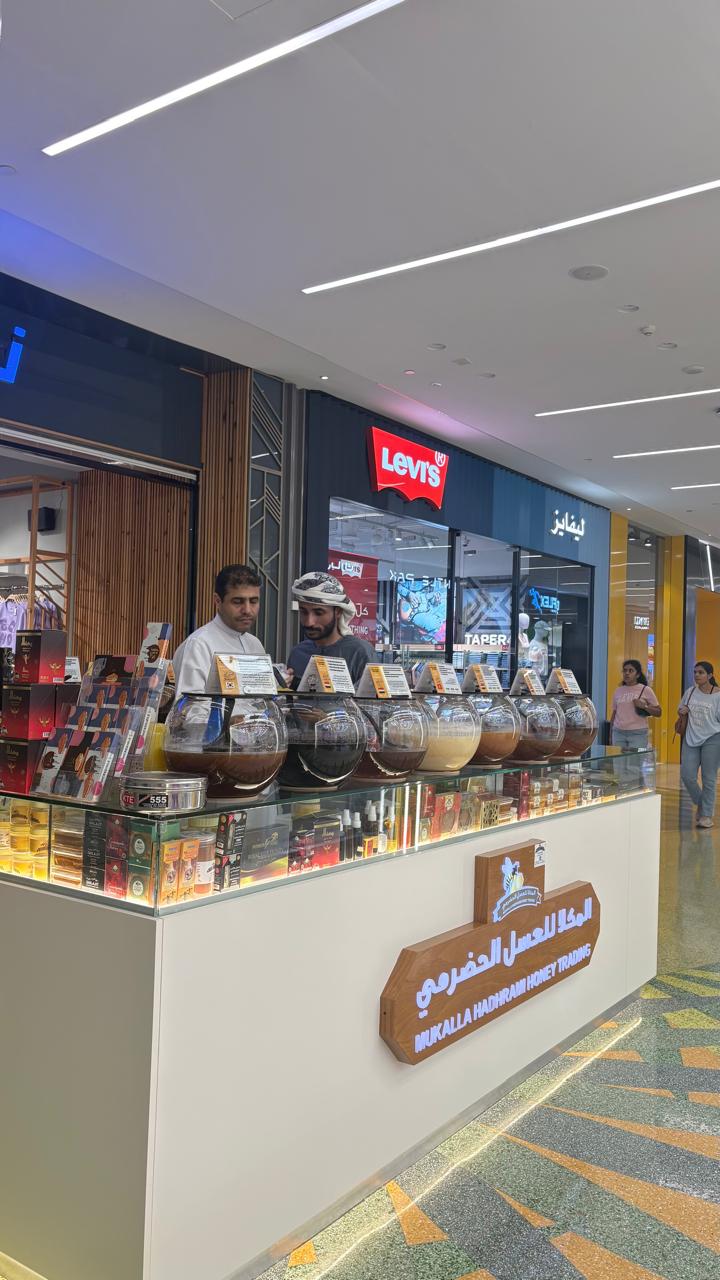 Mukalla Hadhrami Honey Trading counter with honey tasting bowls and staff.
