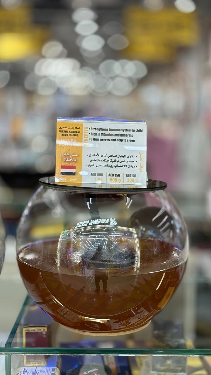 Honey for kids in a spherical glass jar with branded label.